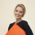 smiling woman standing while holding orange folder